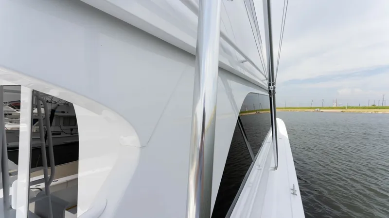 Slide: The Image of Starboard Side Deck with Railings This image showcases the sleek starboard side deck of the 2001 Viking 65 Enclosed Bridge. The polished stainless steel railings provide both safety and style, complementing the yacht's elegant white exterior. The view along the water emphasizes the vessel - 6767201