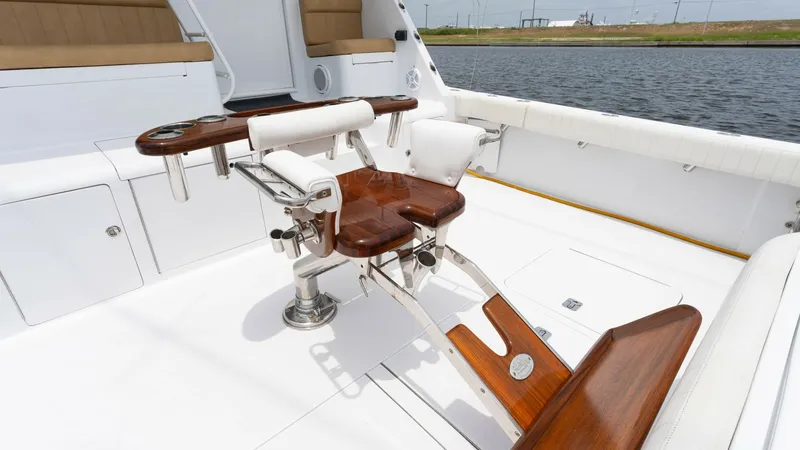 Slide: The Image of Cockpit with Fighting Chair The spacious cockpit of the Viking 65 Enclosed Bridge showcases a beautifully crafted fighting chair, perfect for deep-sea fishing enthusiasts. The teak accents and white upholstery create a luxurious yet practical environment. Ample seating and storage c - 6767193