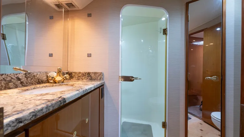 Slide: The Image of En Suite Bathroom with Shower This elegant en suite bathroom on the Viking 65 Enclosed Bridge features a luxurious granite countertop and sleek wood cabinetry, exuding sophistication. The well-lit space is complemented by a modern, glass-enclosed shower, offering both functionality an - 6767182