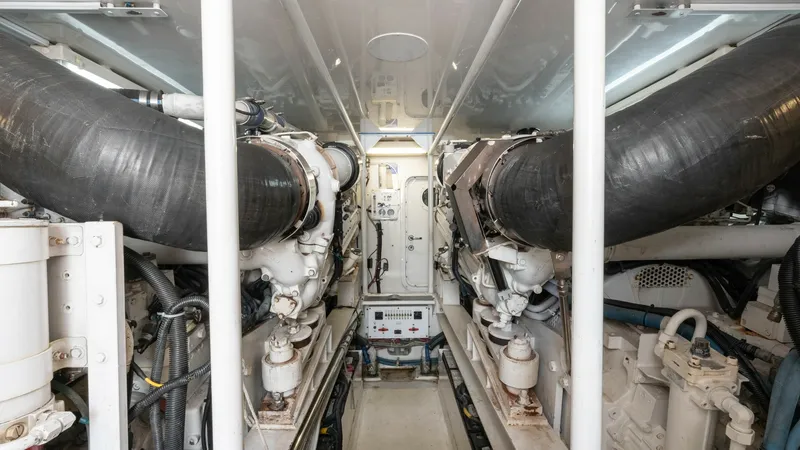 Slide: The Image of Engine Room Overview This image showcases the well-maintained engine room of the 2001 Viking 65 Enclosed Bridge. The space is organized efficiently, with robust exhaust systems and accessible pathways for maintenance. The clean layout and clear labeling enhance ease of operat - 6767194