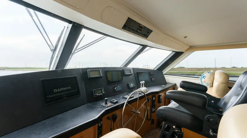 Slide: The Image of Enclosed Bridge Helm Station This image showcases the helm station of the 2001 Viking 65 Enclosed Bridge, featuring advanced Garmin navigation systems. The spacious layout includes plush leather seating, offering comfort and visibility for long voyages. Large windows provide excellen - 6767186