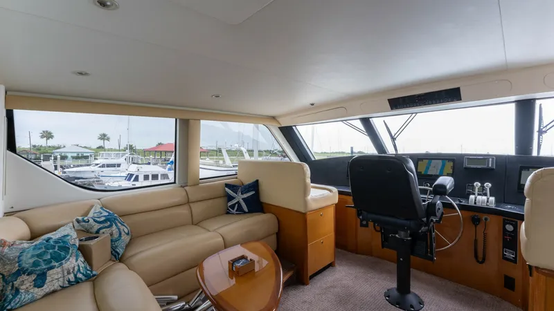 Slide: The Image of Enclosed Bridge Lounge Area The enclosed bridge of the Viking 65 features a spacious lounge area with plush, L-shaped leather seating and decorative cushions, providing a comfortable space for relaxation. The helm station is equipped with advanced navigation controls and offers expa - 6767187