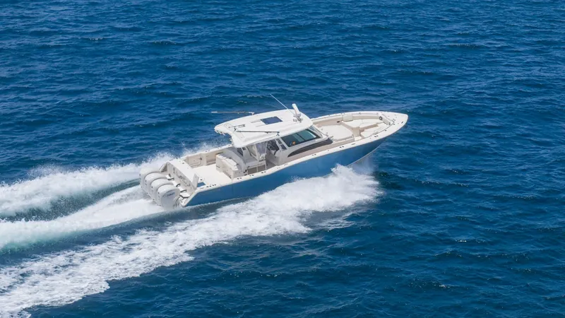 Slide: The Image of Aerial View of Grady-White Canyon 456 This aerial shot captures the sleek design and powerful presence of the 2021 Grady-White Canyon 456. The vessel is shown cutting through the water, showcasing its four robust outboard engines and spacious deck. The elegant lines and sturdy build highlight - 6725196