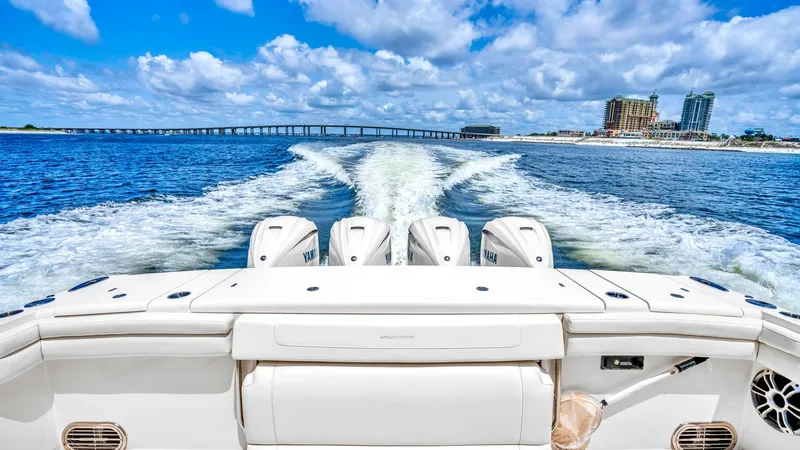 Slide: The Image of Aft Deck with Quad Engines This image showcases the impressive aft deck of the 2021 Grady-White Canyon 456, featuring powerful quad outboard engines. The sleek, white seating area provides comfort and style, complementing the boat's performance capabilities. The expansive view of t - 6725188