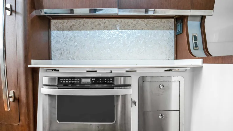 Slide: The Image of Galley with Microwave and Storage This modern galley features a sleek stainless steel microwave complemented by ample storage space. Rich wooden cabinetry adds a touch of elegance, while the contemporary backsplash enhances the stylish design. The area is well-equipped for convenient meal - 6725165