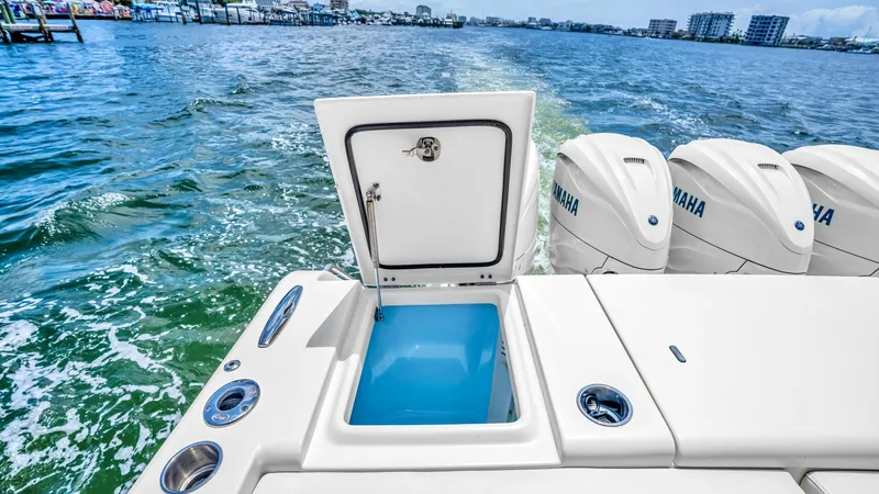 Slide: The Image of Aft Deck with Livewell and Engines This image showcases the aft deck of the 2021 Grady-White Canyon 456, featuring a spacious livewell for optimal bait storage. The sleek design integrates seamlessly with the powerful Yamaha outboard engines, ensuring top performance on the water. The deck - 6725184