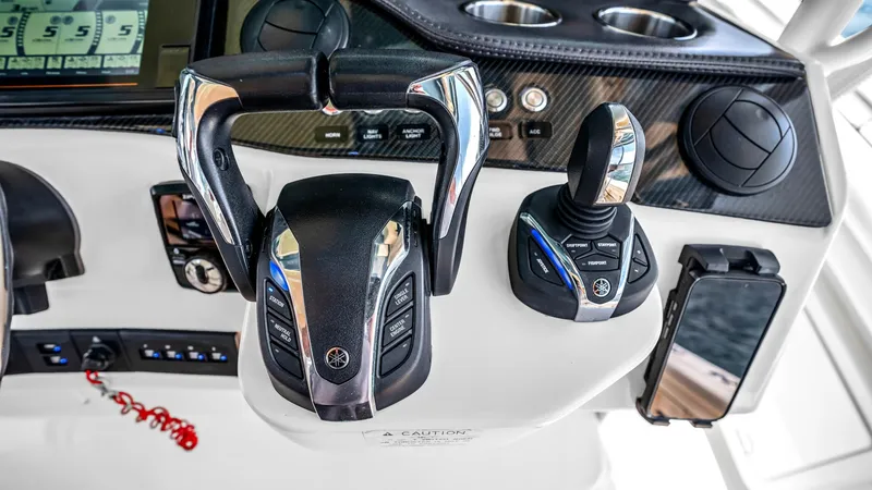 Slide: The Image of Helm Controls and Dashboard The helm station of the Grady-White Canyon 456 showcases advanced throttle controls and a joystick for precise maneuverability. The dashboard features a sleek carbon fiber finish, equipped with a state-of-the-art touchscreen display for navigation and sys - 6725162