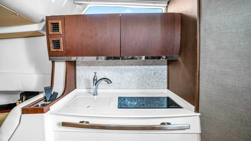 Slide: The Image of Modern Galley with High-End Finishes This sleek galley on the Grady-White Canyon 456 boasts contemporary design with rich wood cabinetry and a polished countertop. Equipped with a single-basin sink and a modern cooktop, it provides all the essentials for on-board dining. The upper cabinets o - 6725164