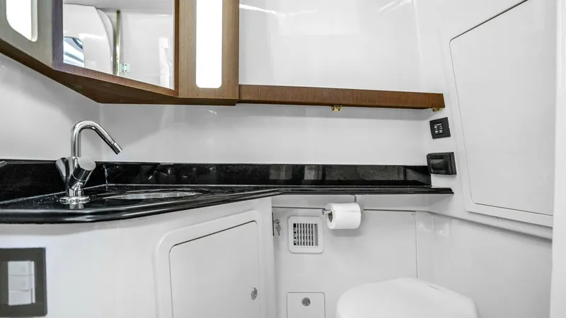Slide: The Image of Modern Onboard Bathroom with Vanity This sleek and modern onboard bathroom features a polished black countertop and an elegant stainless steel faucet, offering both style and practicality. The wooden mirrored cabinet provides ample storage, complemented by the bright overhead lighting that - 6725167