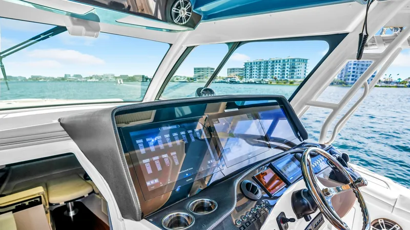 Slide: The Image of Helm Station with Multifunction Display The helm station of the Grady-White Canyon 456 showcases a sleek, modern design with a large multifunction display, providing comprehensive navigation and system control. The ergonomic layout includes a polished steering wheel and easy-to-access controls - 6725158