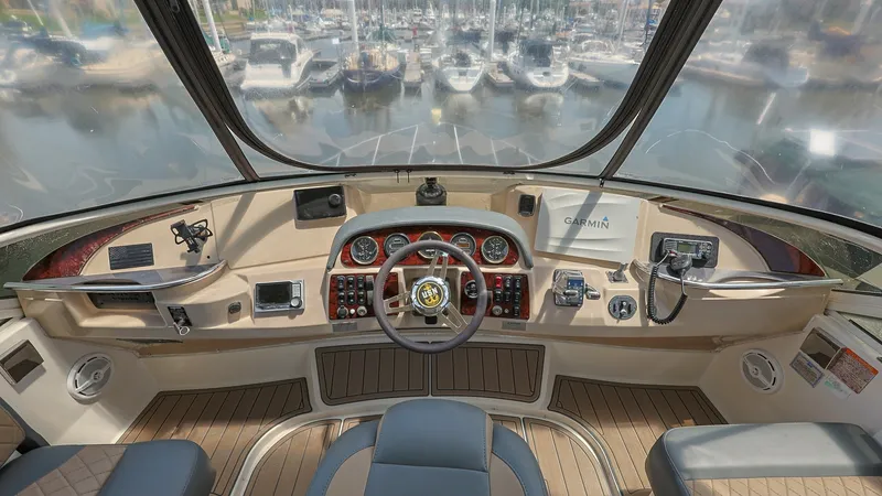 Slide: The Image of Flybridge Helm with Panoramic View The flybridge helm of the 2006 Carver 396 Motor Yacht offers a commanding view with expansive visibility over the marina. Equipped with precision instruments and a Garmin navigation system, this helm ensures smooth sailing and easy maneuverability. The lu - 8273156