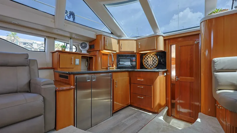 Slide: The Image of Spacious Galley with Skylight The galley of the 2006 Carver 396 Motor Yacht, Serendipity, showcases a sleek design with high-gloss wood cabinetry and modern appliances, including a refrigerator and microwave. Natural light floods the space through expansive skylights, enhancing the ai - 8273154