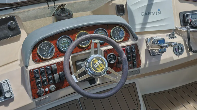 Slide: The Image of Helm Station with Instrument Panel The helm station of the Carver 396 Motor Yacht features a sophisticated instrument panel with classic wood accents and modern navigational equipment. The steering wheel is centrally positioned, surrounded by an array of gauges and controls for easy access - 8273157