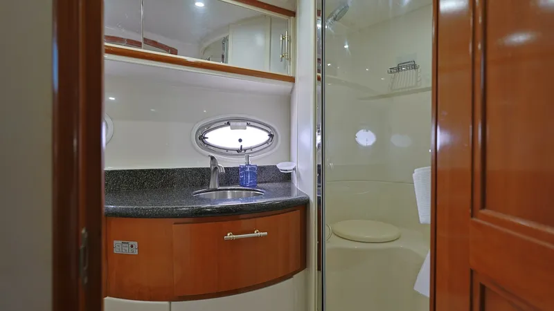 Slide: The Image of Elegant Ensuite Bathroom The ensuite bathroom features a sleek design with a polished granite countertop and integrated sink. A stylish oval porthole allows natural light to enhance the space, while the enclosed shower offers convenience and privacy. Rich wood finishes and modern - 8273180