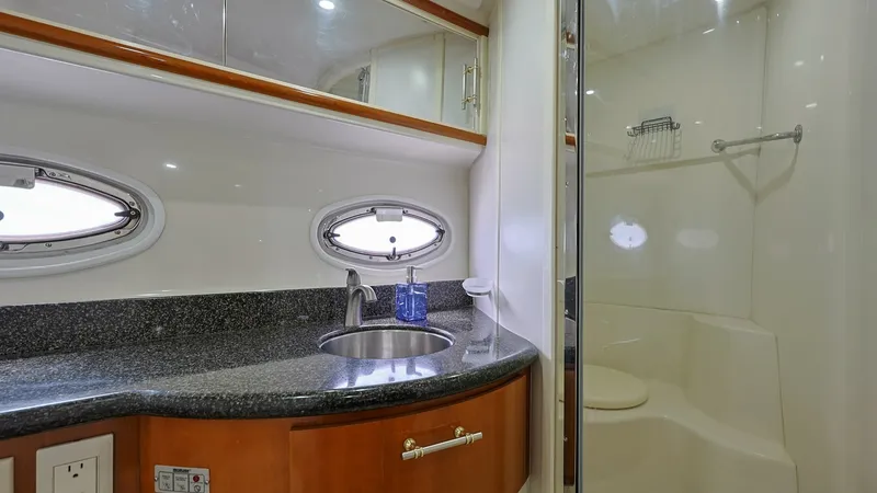 Slide: The Image of Elegant Ensuite Bathroom This well-appointed ensuite bathroom on the 2006 Carver 396 Motor Yacht features a sleek, curved vanity with a polished granite countertop. The space is enhanced by natural light streaming through a stylish porthole window, adding an airy feel. A separate - 8273179