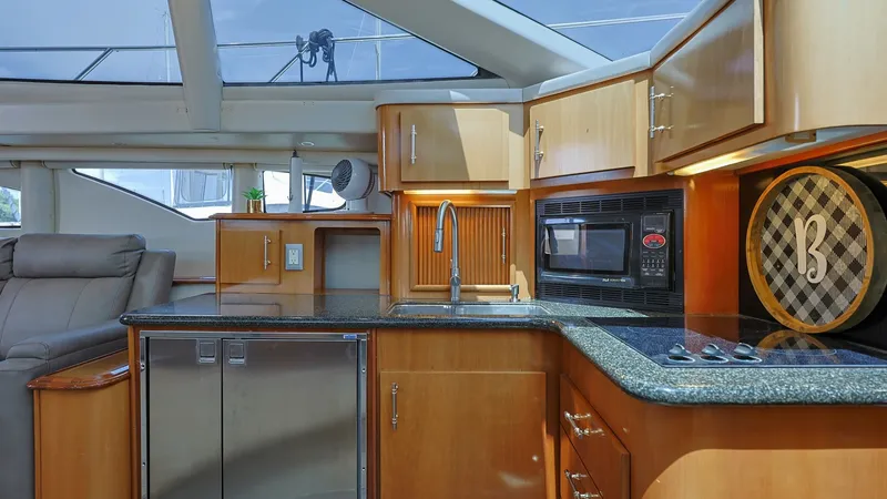 Slide: The Image of Galley with Modern Appliances The galley of the 2006 Carver 396 Motor Yacht features sleek, modern appliances set within rich wood cabinetry, offering both style and functionality. A spacious countertop with integrated sink and stovetop provides ample space for meal preparation. The l - 8273168