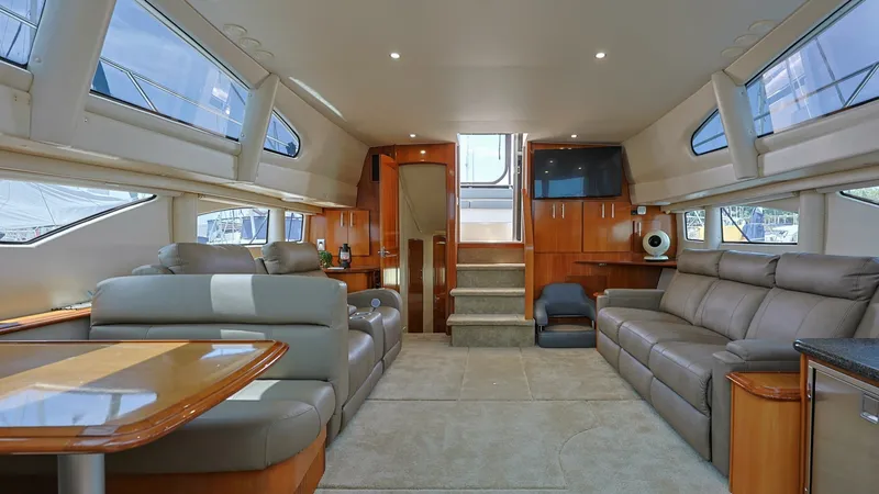 Slide: The Image of Spacious Salon with Panoramic Windows The salon of the 2006 Carver 396 Motor Yacht offers a luxurious and inviting space, featuring plush leather seating and a well-crafted dining area. Expansive panoramic windows flood the interior with natural light, enhancing the elegant wood finishes thro - 8273164