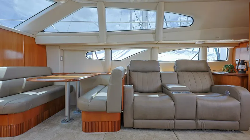 Slide: The Image of Spacious Salon with Panoramic Windows The salon of the 2006 Carver 396 Motor Yacht offers a luxurious and inviting space with plush seating and a well-appointed dinette. Large panoramic windows provide ample natural light, enhancing the open and airy feel. The combination of rich wood finishe - 8273172
