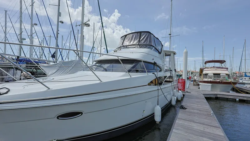 Slide: The Image of Port Side View at Dock The Carver 396 Motor Yacht, Serendipity, is presented dockside, showcasing its sleek exterior lines and robust structure. The flybridge is protected by a canvas enclosure, offering a comfortable space for navigation and relaxation. The vessel's elegant de - 8273191