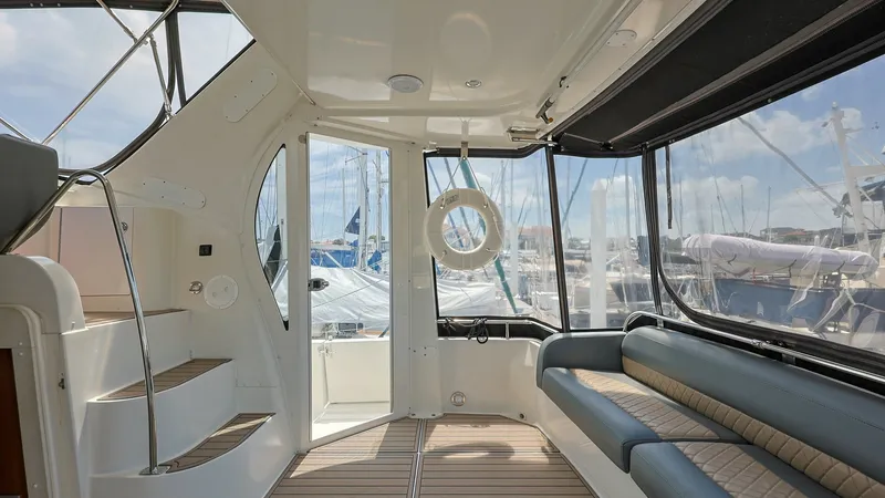 Slide: The Image of Sunlit Aft Deck with Seating The aft deck of the 2006 Carver 396 Motor Yacht offers a spacious and inviting area, perfect for relaxation or entertaining. Featuring plush, upholstered seating that runs along the starboard side, it provides ample comfort. The large windows allow for pa - 8273162