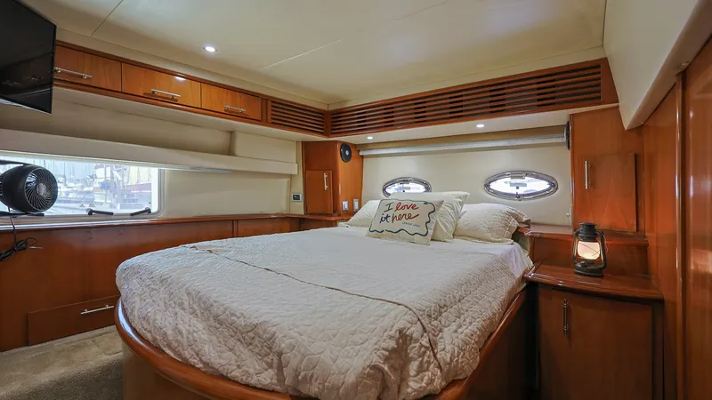 Slide: The Image of Master Stateroom with Queen Berth The master stateroom of the 2006 Carver 396 Motor Yacht features a spacious queen berth adorned with plush bedding. Rich wood cabinetry provides ample storage, complemented by elegant oval portholes that allow natural light to enhance the warm interior am - 8273177