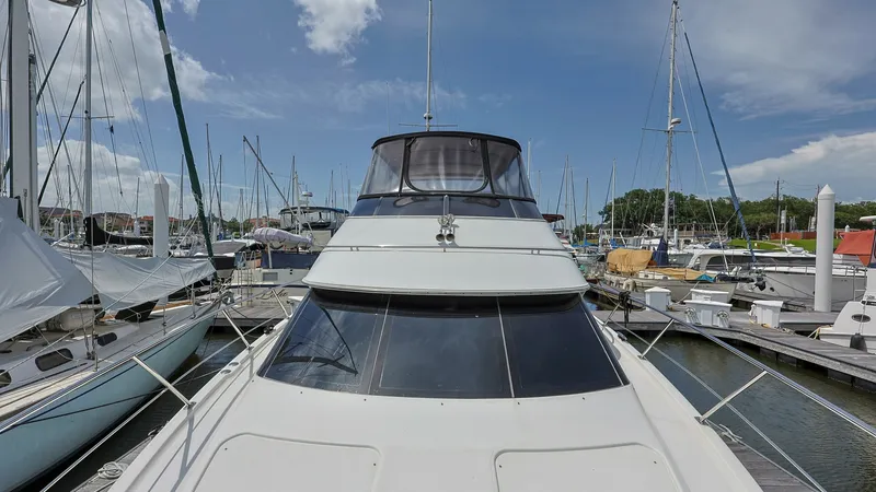 Slide: The Image of Foredeck and Flybridge View This image showcases the expansive foredeck of the 2006 Carver 396 Motor Yacht, Serendipity. The sleek design features large tinted windows providing natural light and visibility to the interior spaces. Above, the flybridge is enclosed with a protective c - 8273186
