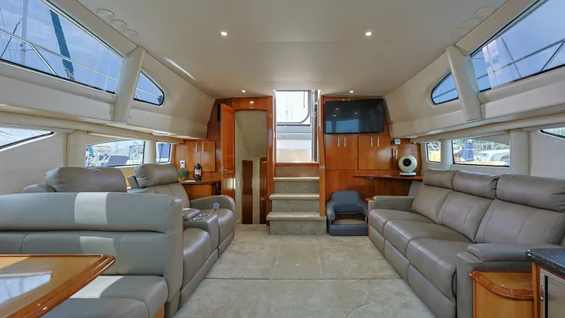 Slide: The Image of Spacious Salon with Ample Seating The salon of the 2006 Carver 396 Motor Yacht showcases a luxurious and spacious interior. It features plush leather seating, rich wood finishes, and expansive windows that flood the space with natural light. The layout includes a built-in entertainment ce - 8273153
