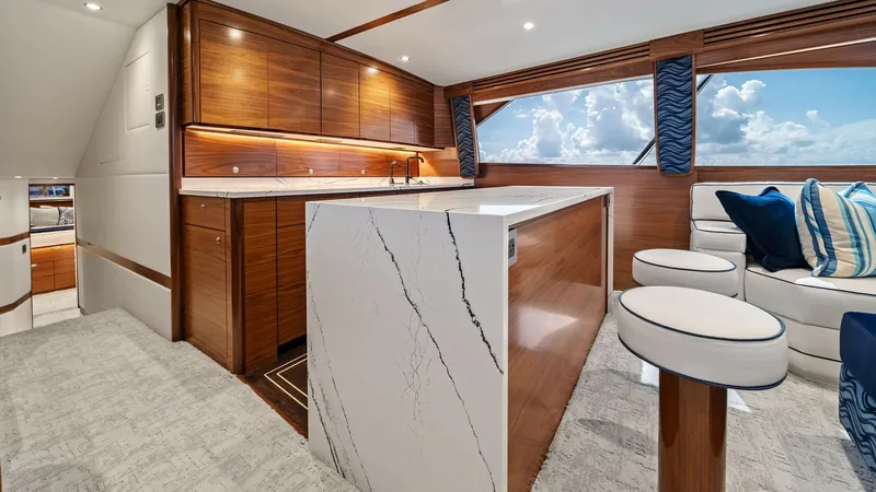 Slide: The Image of Galley and Salon Lounge Area The galley of the 2024 Viking 64 Convertible, Southern Grace, features sleek wooden cabinetry and a stunning marble countertop, offering both functionality and elegance. Adjacent to the galley is a comfortable salon lounge, complete with plush seating and - 7541838