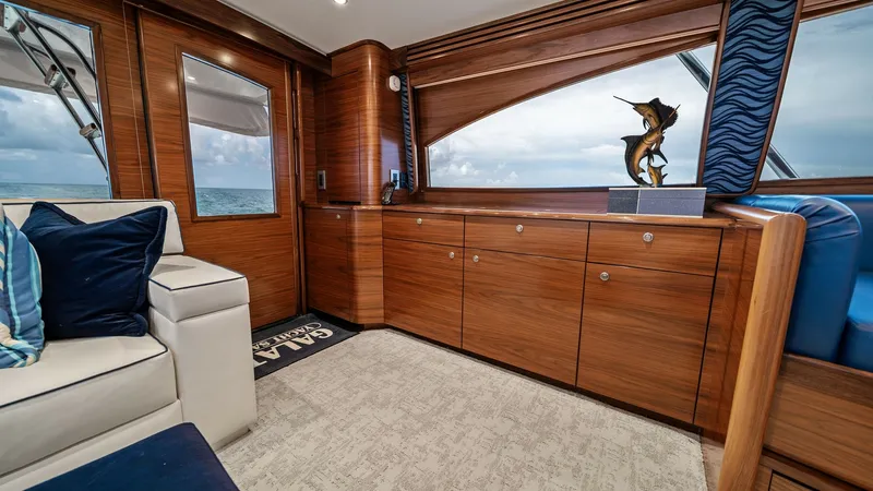 Slide: The Image of Salon with Ocean View Window The salon of the 2024 Viking 64 Convertible 'Southern Grace' features rich wood cabinetry and elegant design. A large window offers stunning ocean views, complemented by plush seating and tasteful decor. The room is well-lit with recessed lighting, creati - 7541834