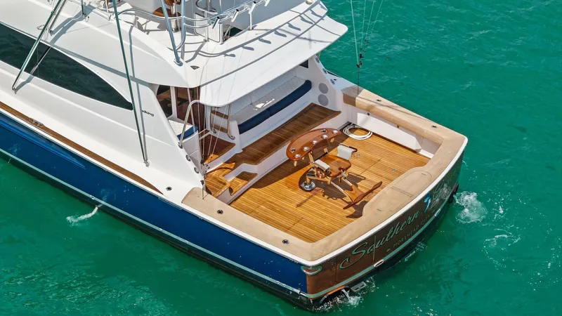 Slide: The Image of Aft Deck with Fishing Setup The aft deck of the 2024 Viking 64 Convertible, Southern Grace, showcases a well-appointed fishing setup with a sturdy fighting chair and ample space for gear. The teak decking complements the sleek lines of the vessel, providing both functionality and el - 7541883