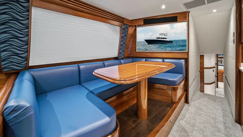Slide: The Image of Salon Dinette with Blue Upholstery The salon dinette of the 2024 Viking 64 Convertible features luxurious blue upholstered seating, offering a comfortable and stylish dining experience. The polished wooden table adds a touch of elegance, perfectly complementing the rich wood finishes throu - 7541825