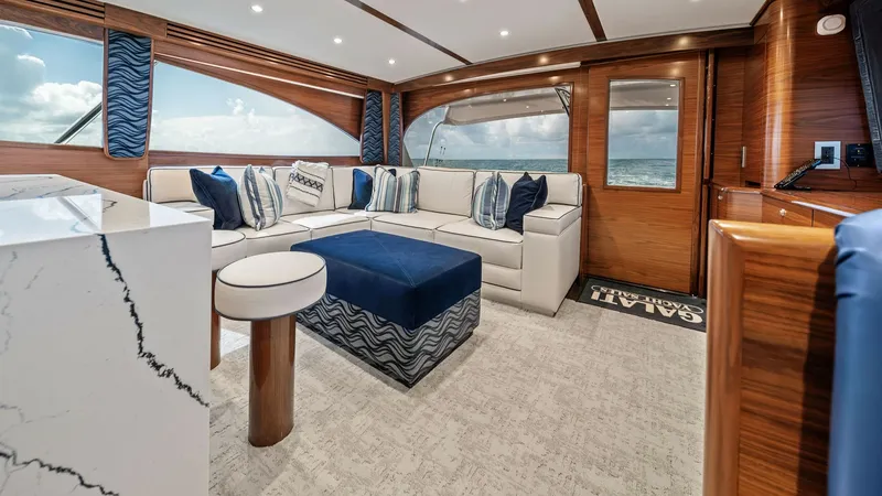 Slide: The Image of Luxurious Salon with Ocean Views The salon of the 2024 Viking 64 Convertible 'Southern Grace' exudes elegance with its plush L-shaped seating and sleek marble accents. Large windows provide stunning ocean views, enhanced by rich wood finishes and ambient lighting. The modern decor and sp - 7541828