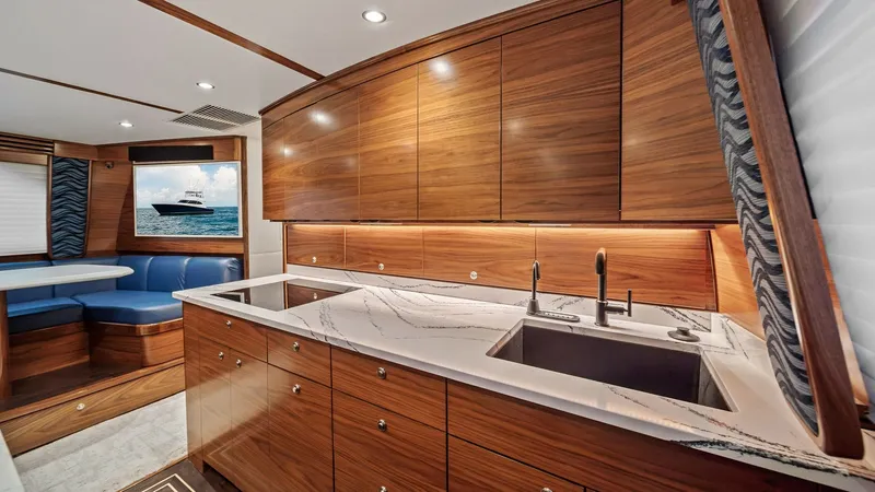Slide: The Image of Modern Galley with Dual Sinks The galley of the 2024 Viking 64 Convertible boasts sleek, high-gloss wood cabinetry and elegant marble countertops. Equipped with dual sinks and ample workspace, it offers both functionality and style. The soft ambient lighting enhances the warm tones, c - 7541817