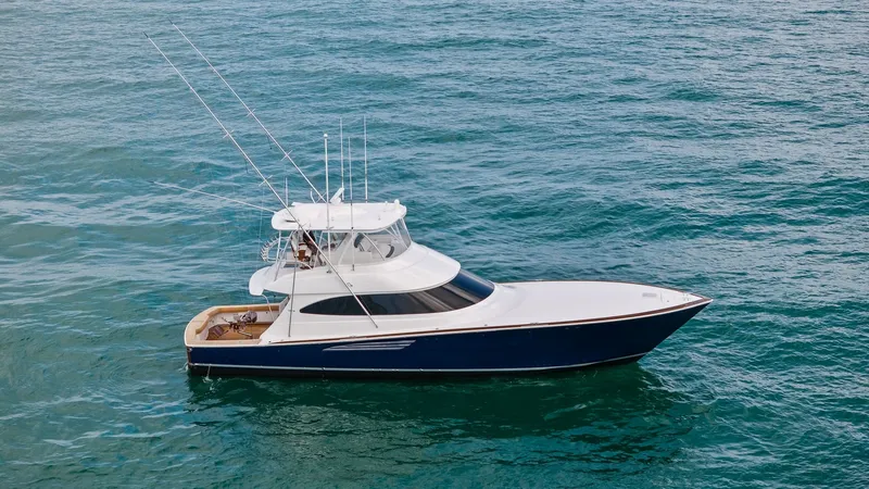 Slide: The Image of Aerial View of Viking 64 Convertible The 2024 Viking 64 Convertible, Southern Grace, showcases its sleek and powerful profile from an aerial perspective. The vessel's elegant blue hull contrasts beautifully with the bright white superstructure, highlighting the spacious flybridge equipped wi - 7541892