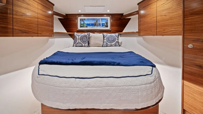 Slide: The Image of VIP Forward Stateroom The forward stateroom of the 2024 Viking 64 Convertible, Southern Grace, exudes elegance with its rich wood cabinetry and plush bedding. Recessed lighting creates a warm and inviting atmosphere, highlighting the spacious layout and ample storage. A stylis - 7541846