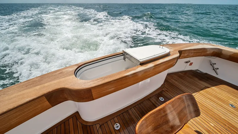 Slide: The Image of Aft Deck with Teak Flooring The aft deck of the 2024 Viking 64 Convertible 'Southern Grace' features exquisite teak flooring that complements the vessel's sleek design. A built-in livewell and spacious seating area provide an ideal setting for both relaxation and fishing adventures. - 7541808