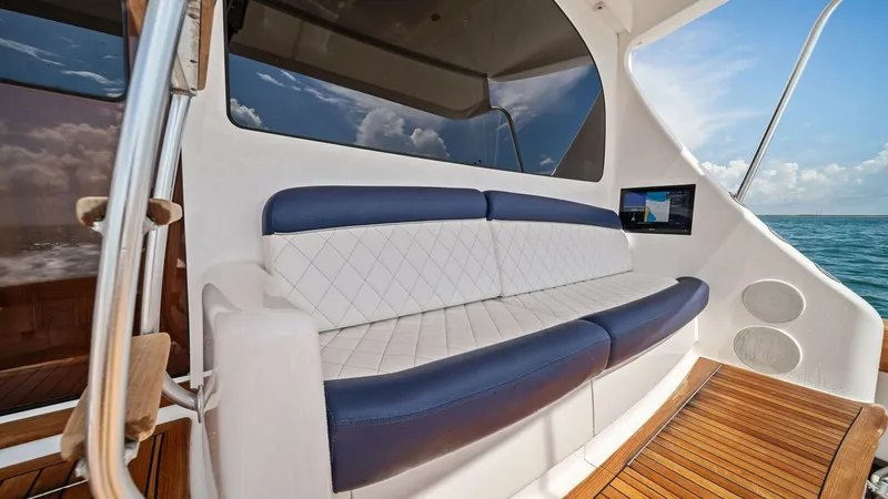 Slide: The Image of Aft Deck Seating Area This inviting aft deck seating area on the 2024 Viking 64 Convertible, 'Southern Grace,' features plush, diamond-stitched upholstery in a sleek navy and white color scheme. The space is designed for comfort and functionality, offering a perfect spot for r - 7541809