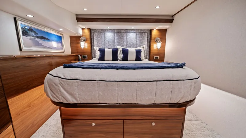Slide: The Image of Luxurious Master Stateroom The master stateroom of the 2024 Viking 64 Convertible, Southern Grace, exudes elegance with its plush bedding and sophisticated wood finishes. Ambient lighting and stylish wall sconces create a warm and inviting atmosphere, complemented by ample storage - 7541841