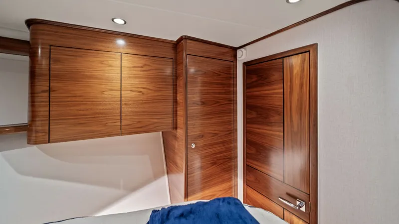Slide: The Image of VIP Stateroom with Rich Wood Finish This elegant guest stateroom aboard the 2024 Viking 64 Convertible showcases exquisite wood cabinetry and trim, providing a warm and inviting atmosphere. The room is accented by recessed lighting, enhancing the natural tones of the wood. A plush bed with - 7541850
