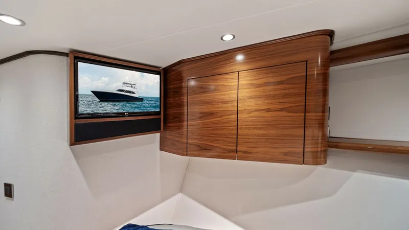 Slide: The Image of VIP Stateroom with TV This guest stateroom on the 2024 Viking 64 Convertible features a sleek, built-in entertainment system with a flat-screen TV, perfect for relaxation. The warm, high-gloss wood cabinetry provides ample storage while adding a touch of luxury to the space. S - 7541849