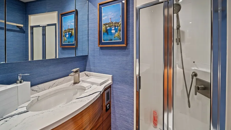 Slide: The Image of Guest Bathroom The guest bathroom on the 2024 Viking 64 Convertible, Southern Grace, features a sleek, modern design with elegant finishes. The marble countertop complements the rich wood cabinetry, while the glass-enclosed shower adds a touch of sophistication. Nautica - 7541857