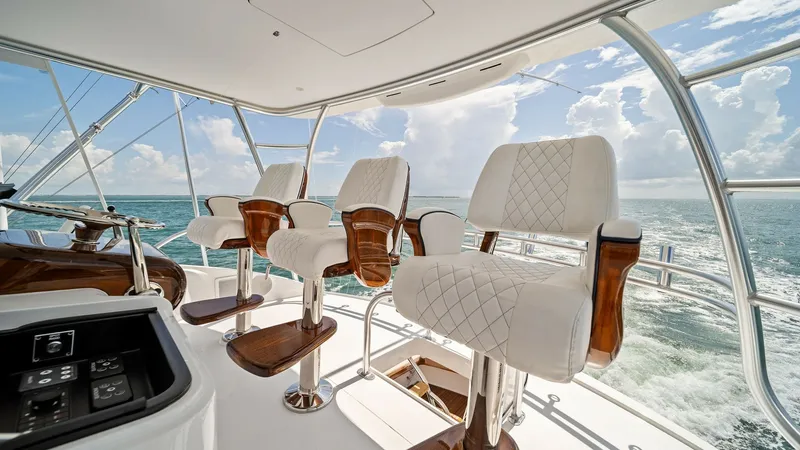 Slide: The Image of Flybridge Helm Seating Area Experience luxury and command with the sophisticated helm seating on the flybridge of the 2024 Viking 64 Convertible. Featuring plush, quilted white leather seats with rich wooden accents, this area offers both comfort and style. Enjoy panoramic ocean vie - 7541859