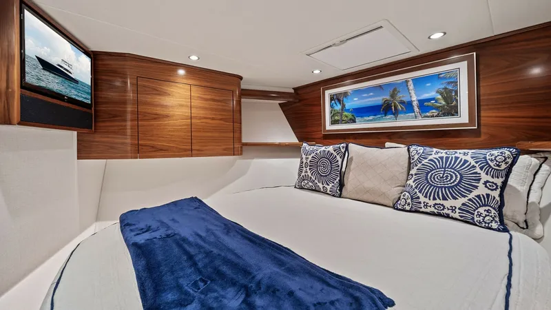 Slide: The Image of VIP Stateroom The starboard guest stateroom features elegant wood paneling and a plush double berth adorned with nautical-themed pillows and a cozy blue throw. Recessed lighting creates a warm ambiance, complementing the vibrant artwork and wall-mounted TV for entertai - 7541848