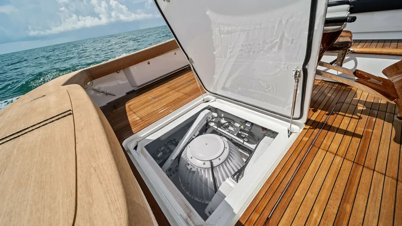 Slide: The Image of Engine Room Access Hatch The image showcases the sleek engine room access hatch on the Southern Grace, a 2024 Viking 64 Convertible. The hatch opens to reveal a neatly organized mechanical space, emphasizing the yacht's attention to engineering excellence. The teak decking adds a - 7541872