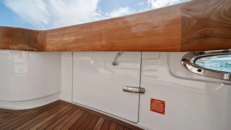 Slide: The Image of Cockpit Storage and Teak Decking This image showcases the cockpit area of the 2024 Viking 64 Convertible, featuring elegant teak decking and a robust storage compartment. The high-gloss wood finish on the gunwale adds a touch of sophistication, while the secure latch ensures practicality - 7541807