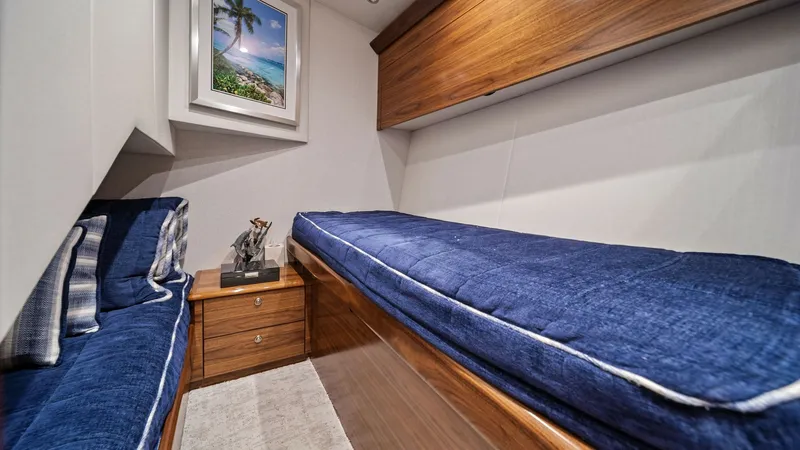 Slide: The Image of Guest Cabin with Twin Berths This cozy guest cabin on the 2024 Viking 64 Convertible features twin berths adorned with plush blue cushions, providing a comfortable retreat. The warm wood finishes and ample storage space offer both style and functionality. The cabin is accentuated by - 7541854
