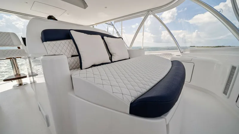 Slide: The Image of Flybridge Lounge Seating Area The flybridge of the 2024 Viking 64 Convertible, Southern Grace, features a luxurious lounge seating area. It boasts plush, quilted upholstery in a sophisticated white and navy color scheme, complemented by large cushions for added comfort. The expansive - 7541870