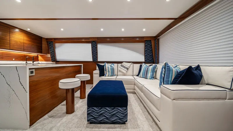 Slide: The Image of Luxurious Salon with Seating and Bar The salon of the 2024 Viking 64 Convertible, 'Southern Grace,' features an elegant blend of comfort and style. The plush L-shaped seating with vibrant blue accent pillows invites relaxation, while the sleek bar area with modern stools offers a perfect spo - 7541813