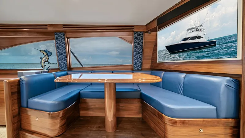 Slide: The Image of Elegant Dinette Area This inviting dinette area on the 2024 Viking 64 Convertible features plush blue leather seating and a beautifully crafted wooden table, creating a perfect space for dining or socializing. Large windows allow for panoramic views, enhancing the open and ai - 7541839