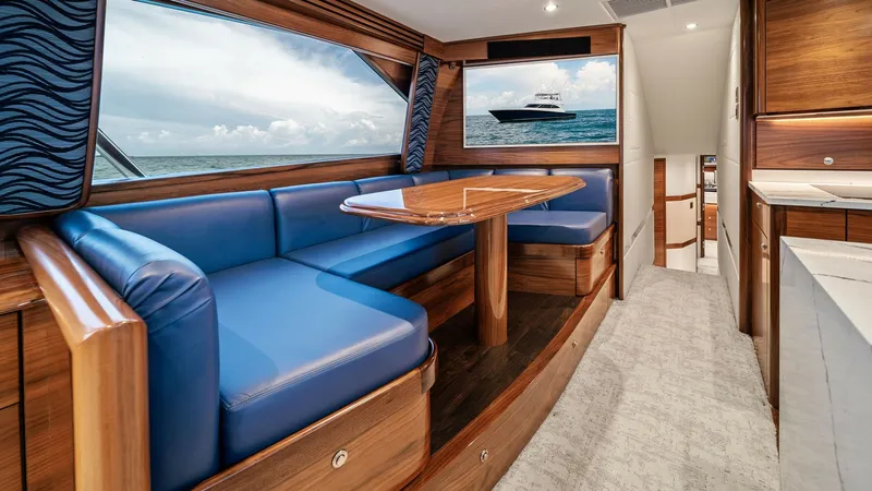 Slide: The Image of Elegant Interior Dining Area The dining area of the Viking 64 Convertible 'Southern Grace' features plush blue seating and a sleek wooden table, offering a sophisticated yet comfortable space for meals. Large windows provide panoramic ocean views, enhancing the open and airy atmosphe - 7541831